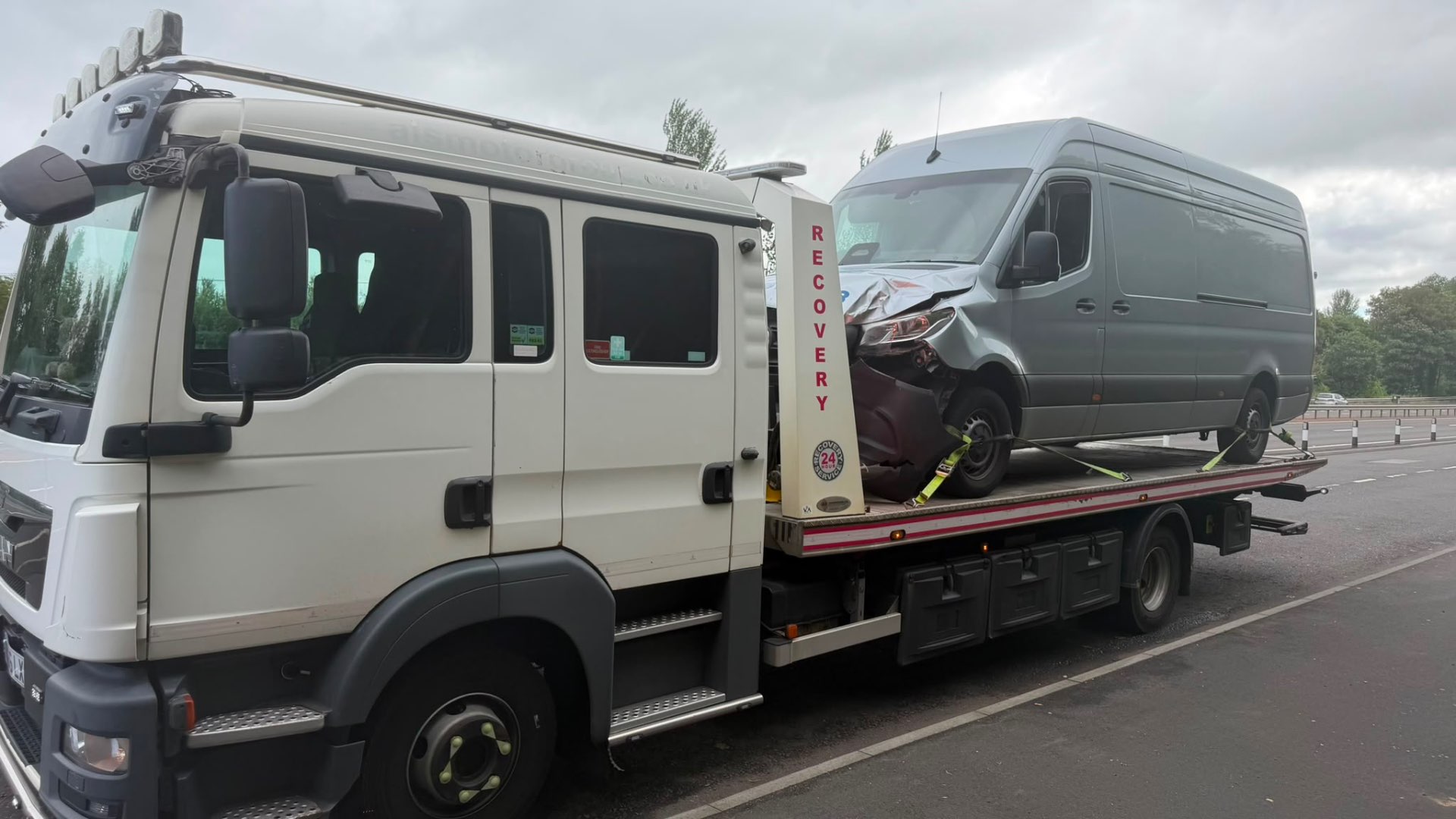 MAN recovery truck with accident-damaged Mercedes Sprinter van on motorway